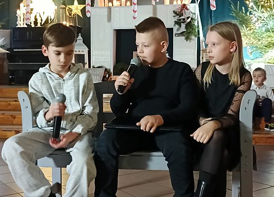 2 chłopców i dziewczynka siedzą na ławce i rozmawiają