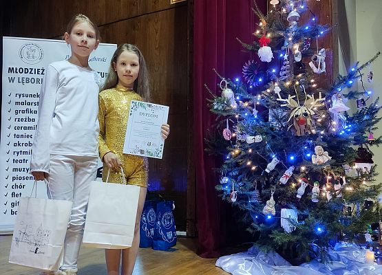Hania i Zosia z nagrodami przy choince ozdobionej ich ozdobami