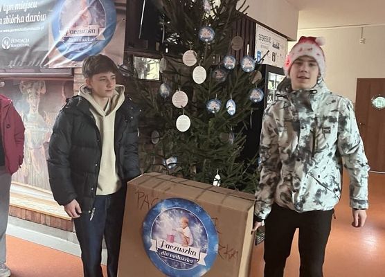 Uczniowie przenoszą karton z darami