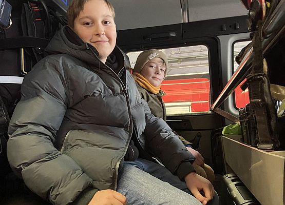chłopcy siedzą w wozie strażackim