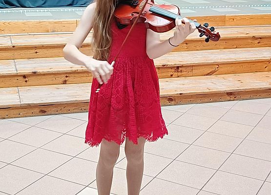 dziewczynka w czerwonej sukience gra na skrzypcach