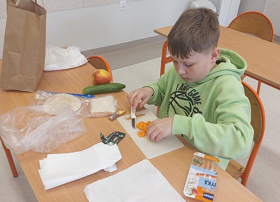 Oliwier tworzy kanapkę z marchewki i parówki