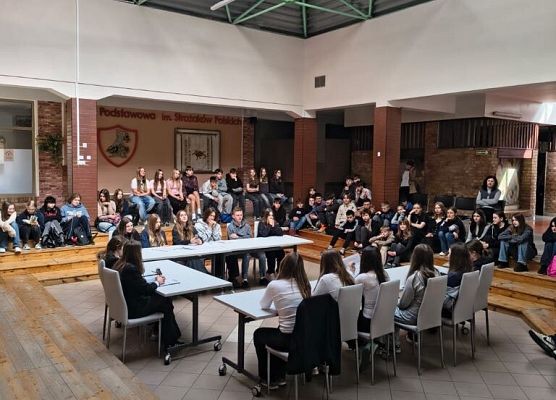 Uczniowie zgromadzili się na patio , siedzą i debatują.