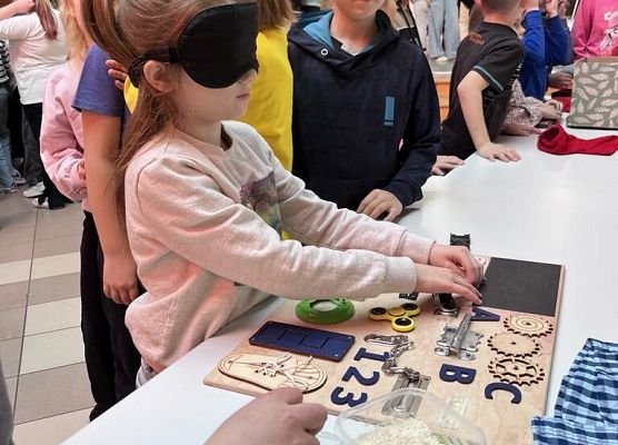 Uczniowie stoją przy stolikach i wykonują różne zadania