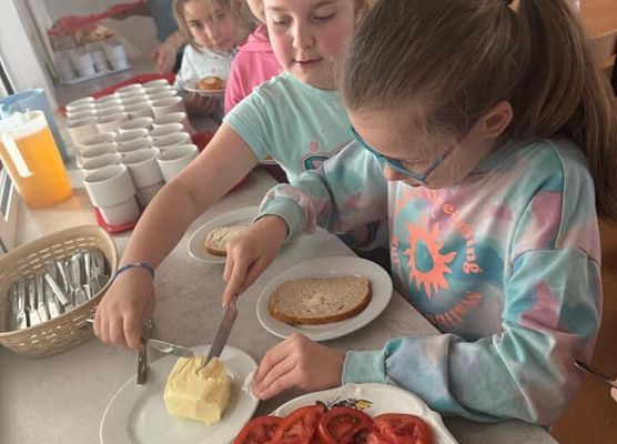 dziewczynki smarują chlebek masłem