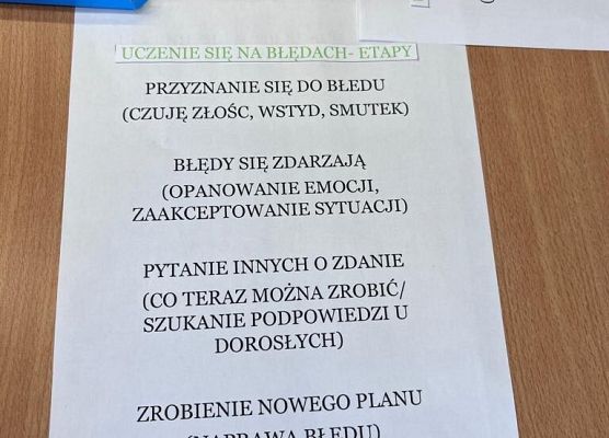 Na stole leżą kartki z zadaniami dla uczniów. Uczniowie wypełniają je mazakami