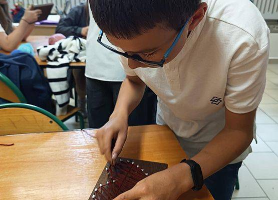 uczeń nawleka wełnę