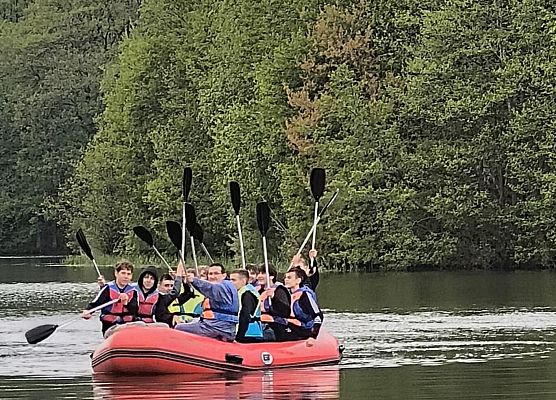 chłopcy płyną pontonem po jeziorze