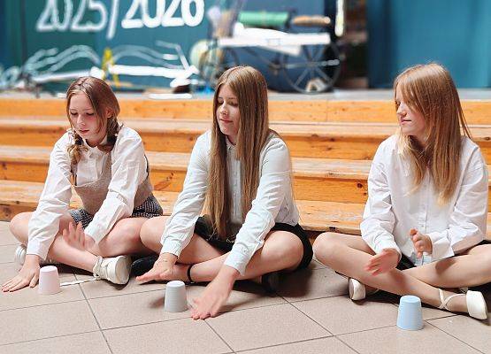 trzy dziewczynki grają na kubkach