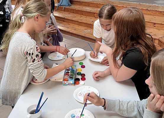 Uczniowie malują na papierowych talerzach kropki