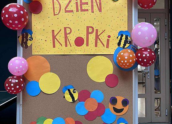 Tablica na której przyczepione jest hasło dzień kropki oraz kolorowe balony