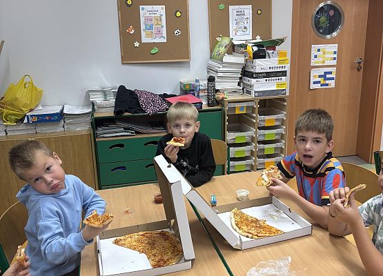 chłopaki jedzą pizze