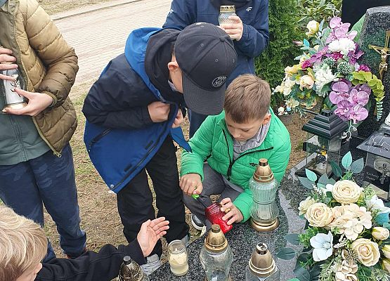 Uczniowie zapalają znicze