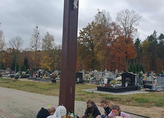 Uczniowie zapalają znicze pod krzyżem