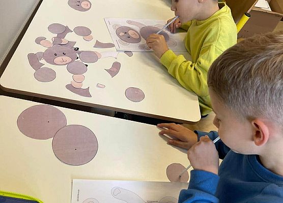 Uczniowie układają postać misia przy pomocy słomki