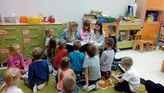 Grafika #0: Starsze uczennice czytają młodszym